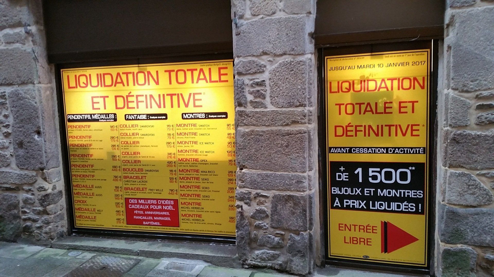 Une devanture avec un sticker jaune sur la vitrine indiquant une liquidation totale