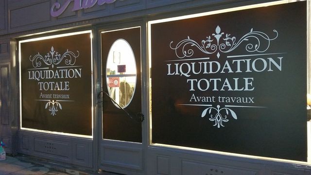 Vitrine avec inscription  LIQUIDATION TOTALE en blanc sur fond noir. Annonce avant travaux.
