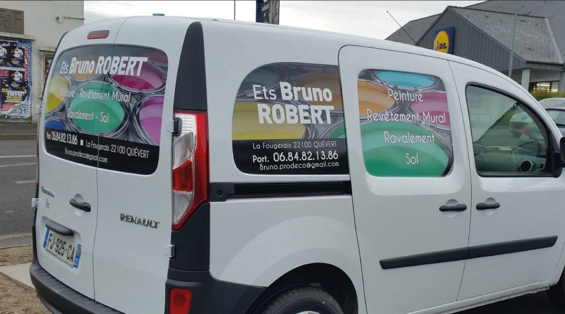 Fourgonnette Renault blanche avec publicité Ets Bruno ROBERT ; stationnée dans une rue.