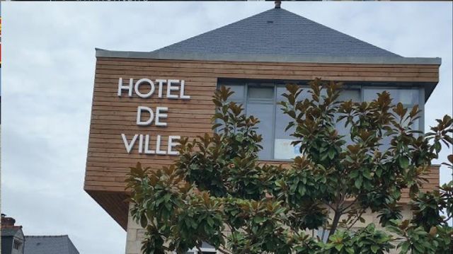 Bâtiment de l'Hôtel de Ville avec boiseries, lettres blanches et toit foncé.