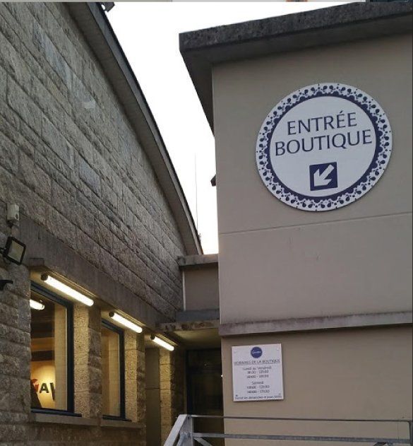 Panneau ENTRÉE BOUTIQUE avec une flèche. Entrée de l'immeuble aux murs beiges.