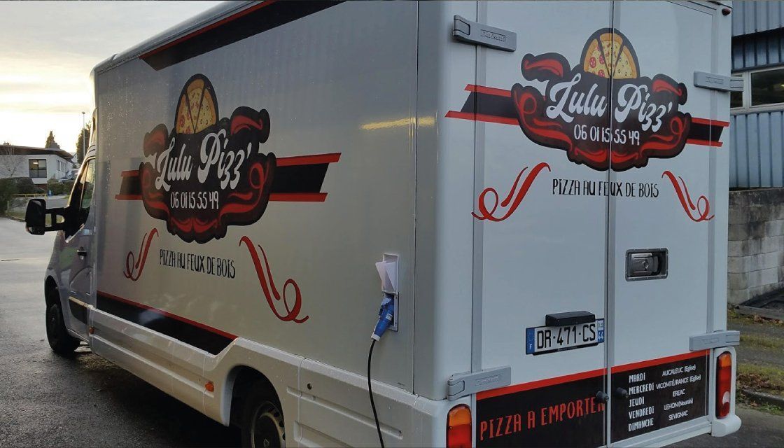 Food truck blanc avec le logo Lula Pizz sur le côté, garé à l'extérieur.