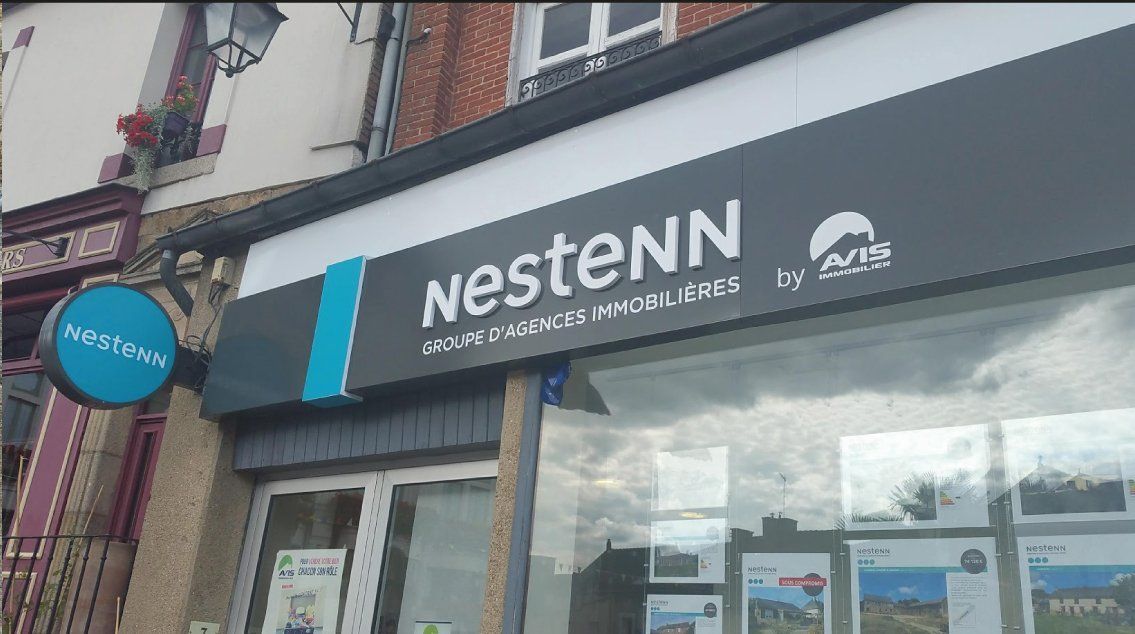 Enseigne d'agence immobilière Nestenn avec un logo bleu sarcelle et gris, marque Avis, extérieur de la vitrine.