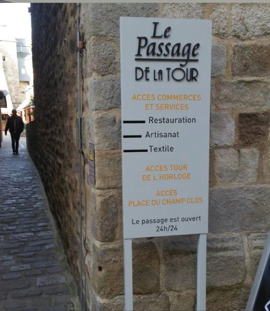 Panneau Le Passage DE LA TOUR dans un passage en pierre, indiquant l'accès aux commerces, restaurants et autres services.