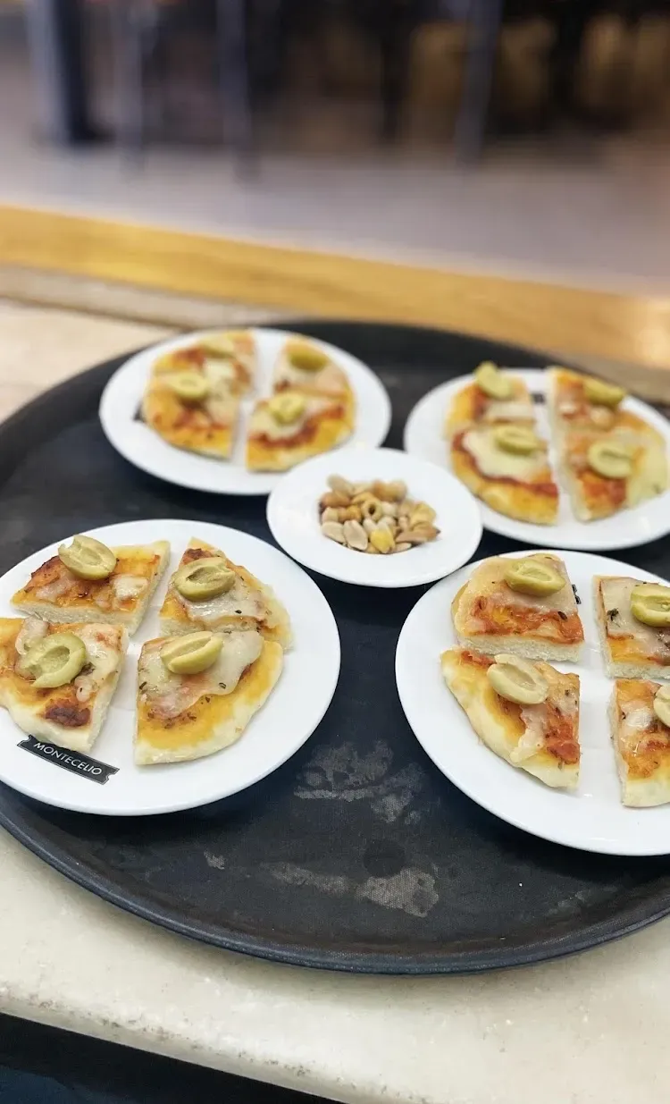 Dos cócteles oscuros con cáscaras de naranja y hielo, servidos con maní en una encimera de mármol.