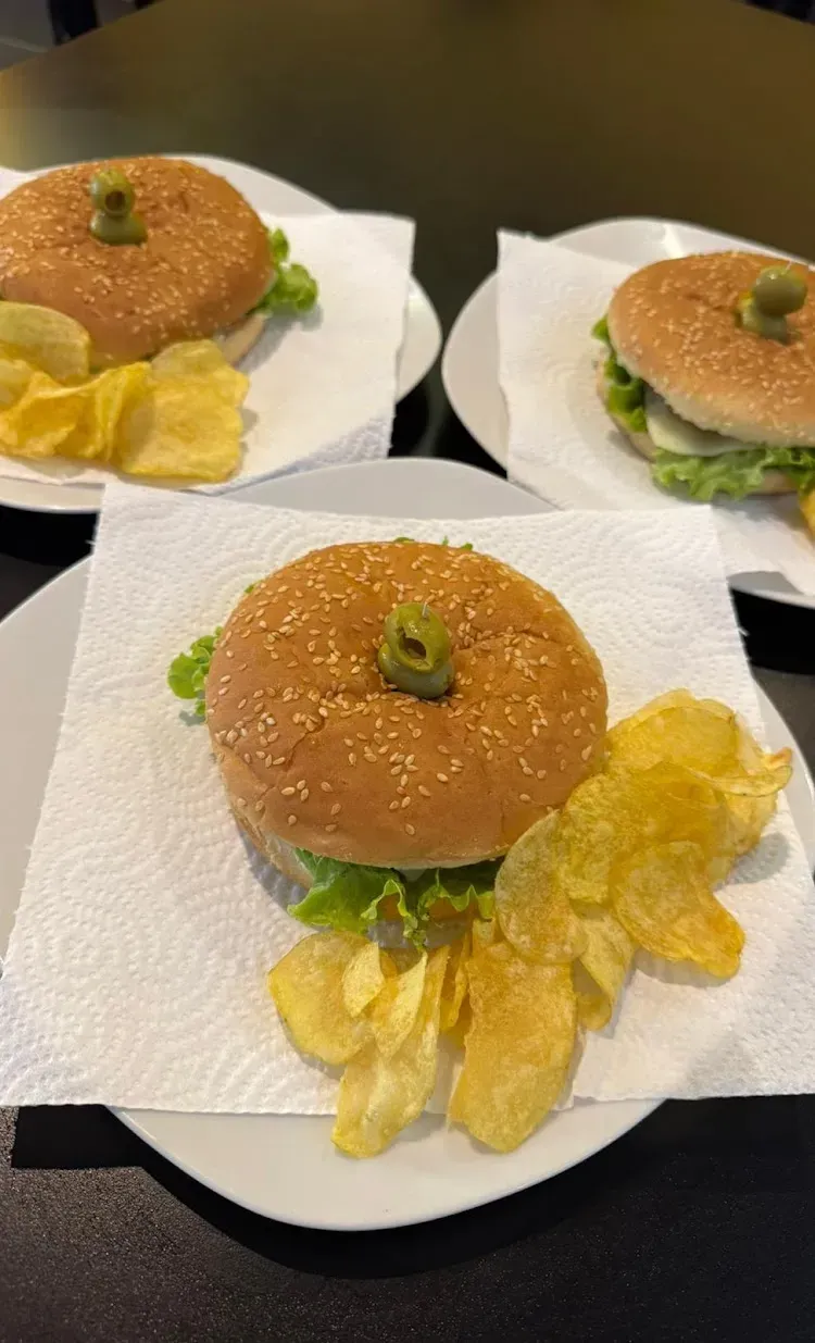 Tres hamburguesas en platos con patatas fritas. 