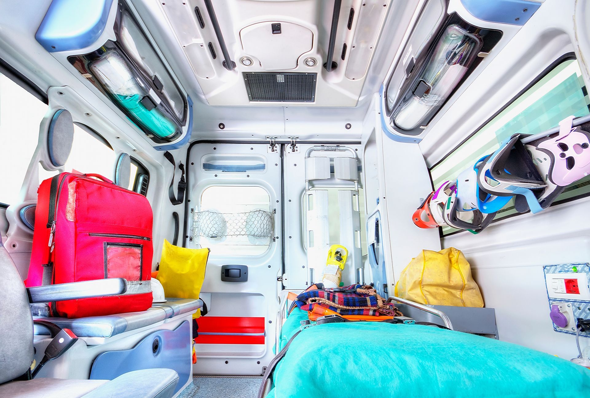 Intérieur d'une ambulance, équipée de matériel médical, d'espaces de rangement et d'un lit pour patient.