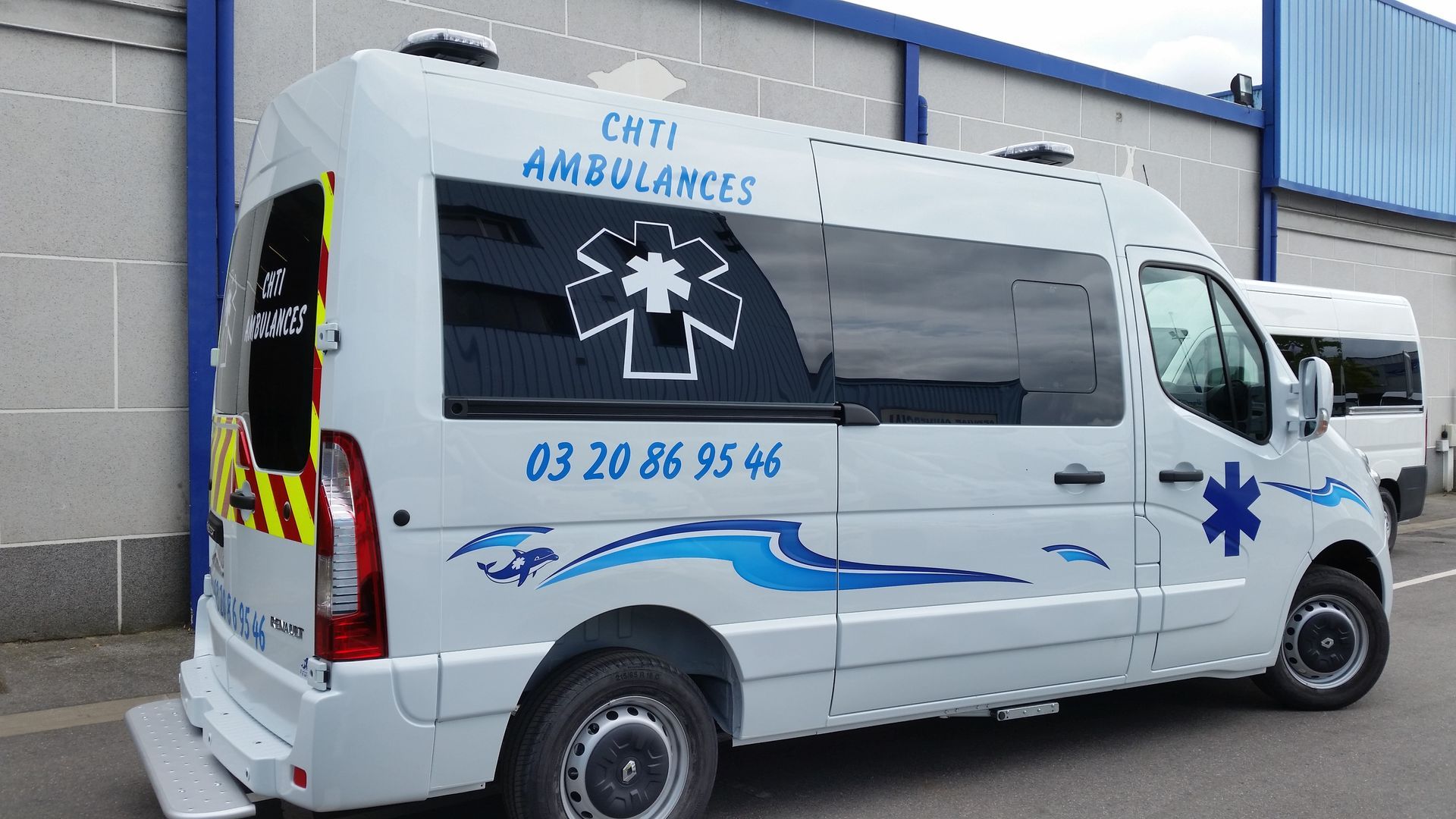Ambulance blanche avec des touches de bleu ; inscription CMTJ AMBULANCES. Étoile de vie sur le côté. Numéro de téléphone visible.