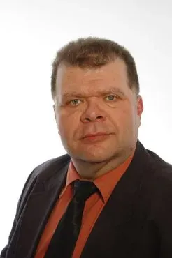 Mann im Anzug mit Krawatte, der mit ernster Miene direkt in die Kamera blickt.