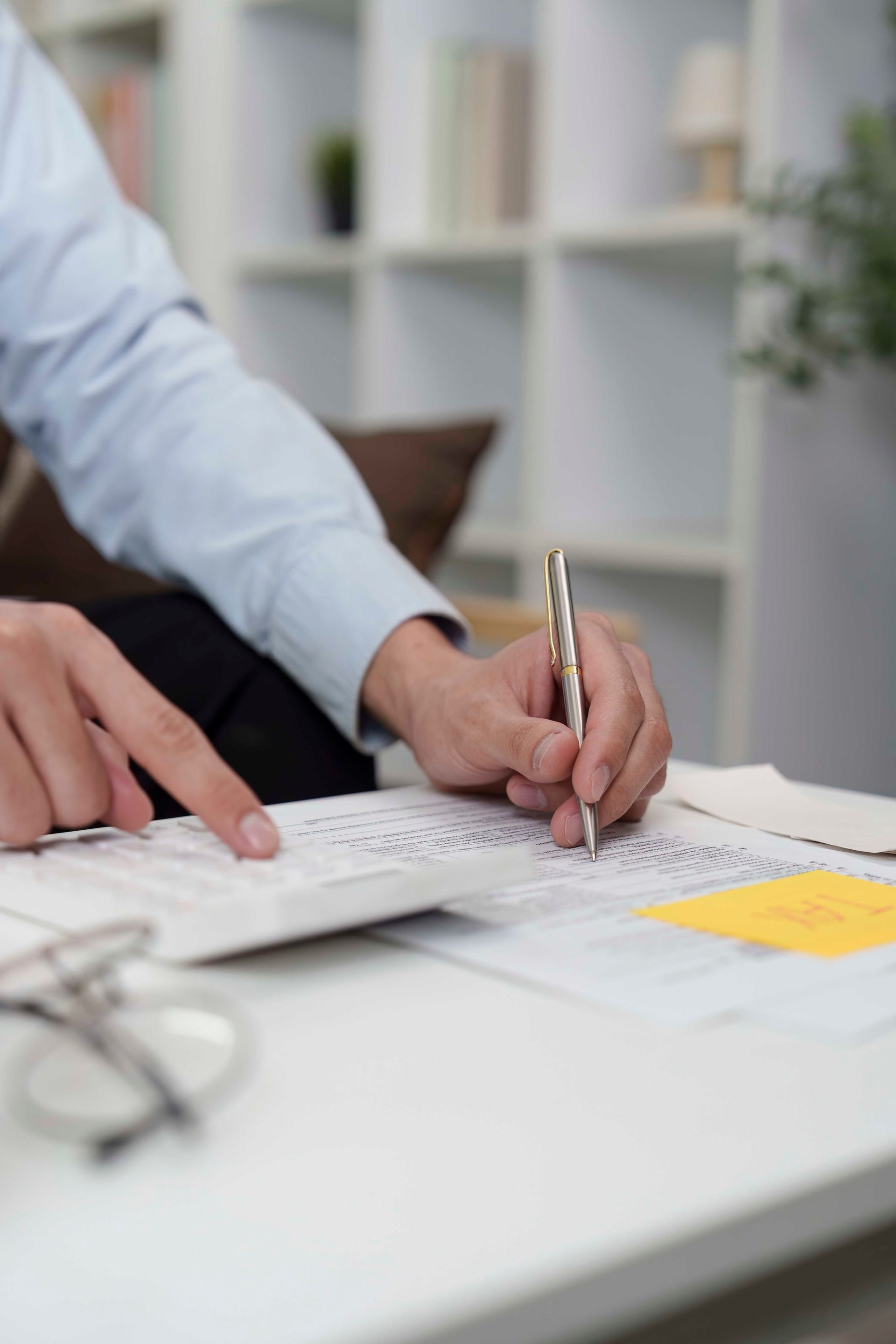 Eine Person schreibt auf Papier und benutzt dabei einen Stift und einen Taschenrechner.