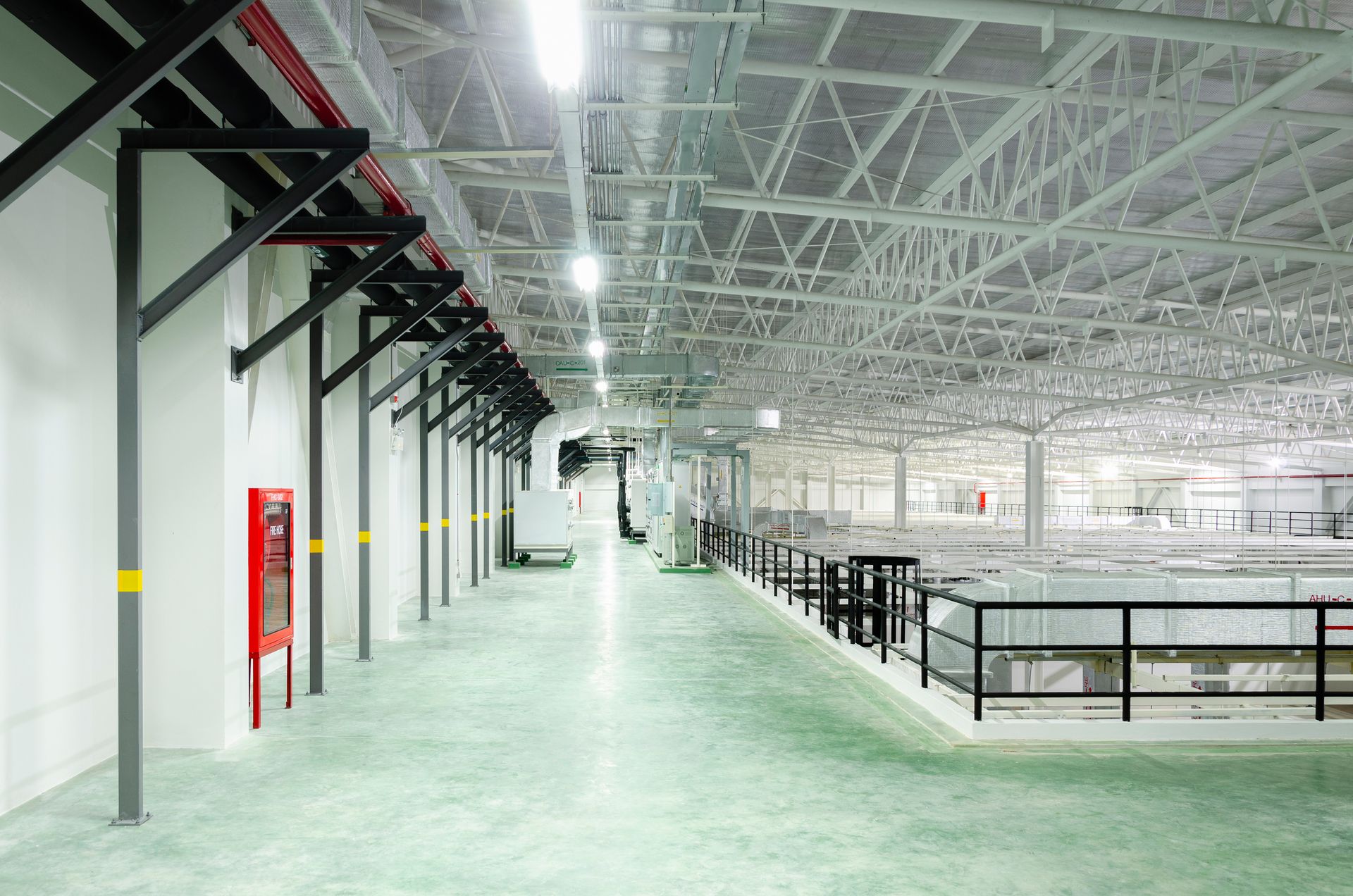Eine große leere Lagerhalle mit grünem Boden und weißen Wänden.