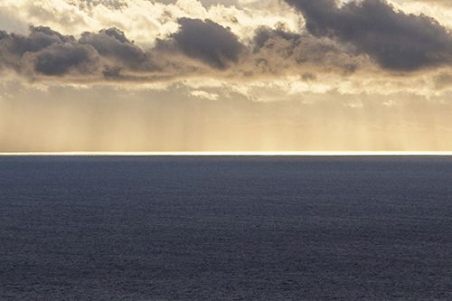 Die Sonne scheint durch die Wolken über dem Ozean.