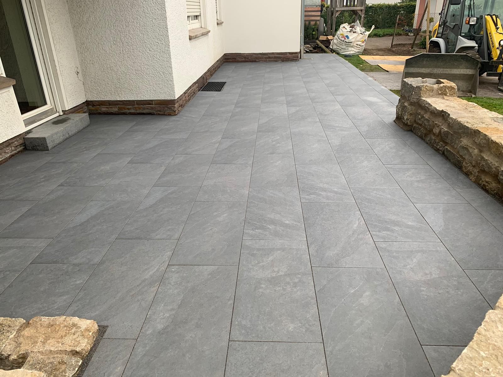 Grau geflieste Terrasse vor einem Gebäude.