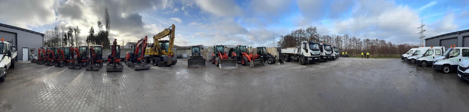 Fahrzeuge, darunter Bagger, Lastwagen und Lieferwagen, parkten unter bewölktem Himmel.