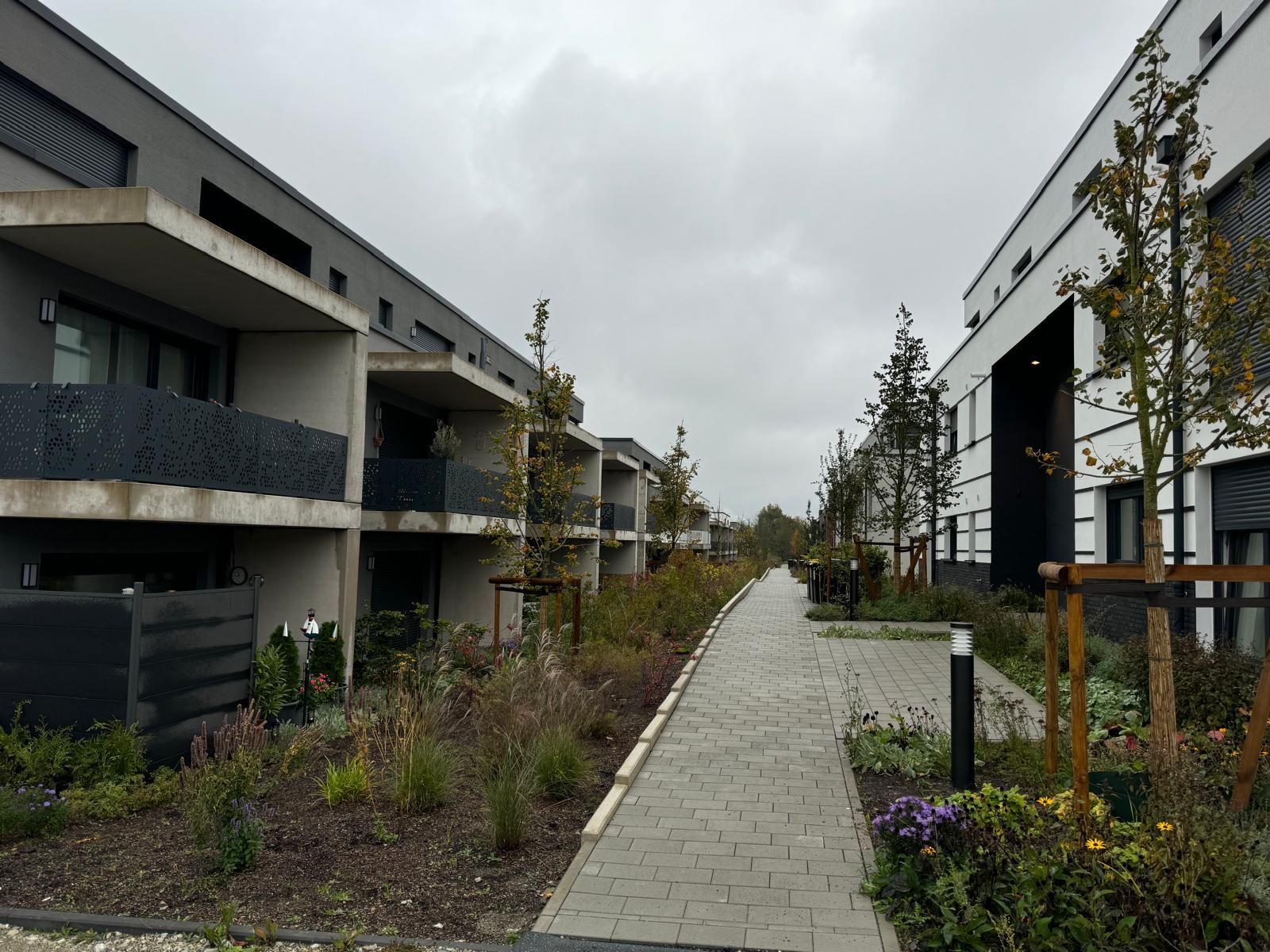 Fußweg zwischen zwei modernen Wohnhäusern an einem bewölkten Tag.