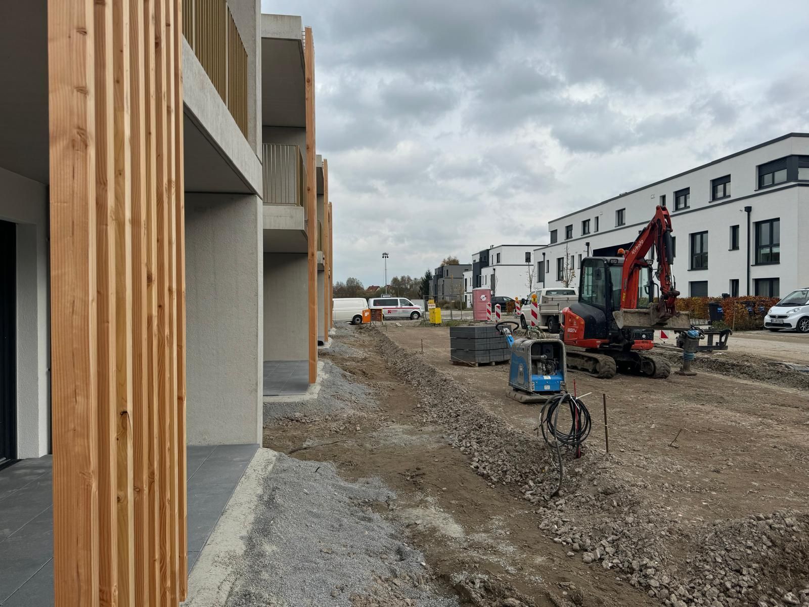 Baustelle mit Gebäuden und schweren Maschinen an einem bewölkten Tag.