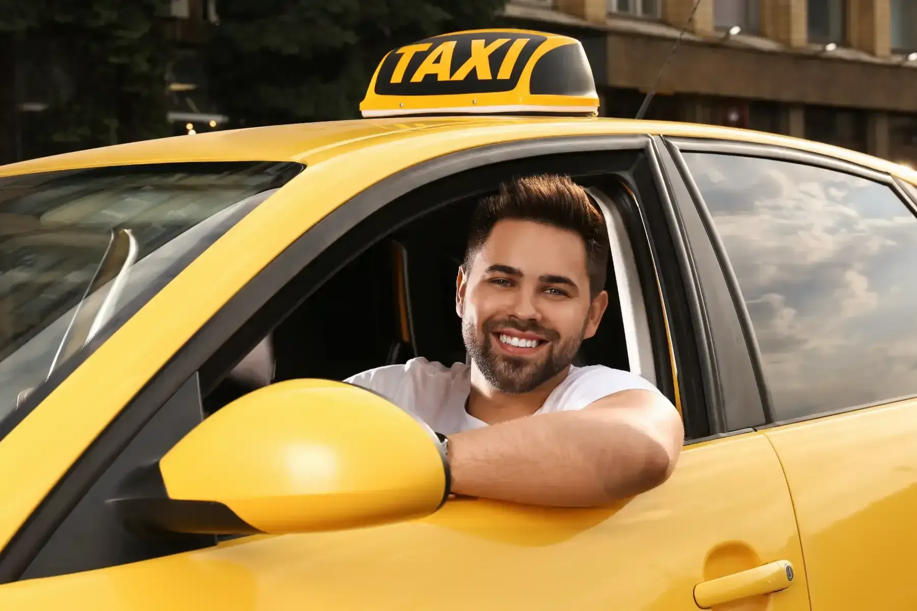 Un hombre está sentado en el asiento del conductor de un taxi amarillo.
