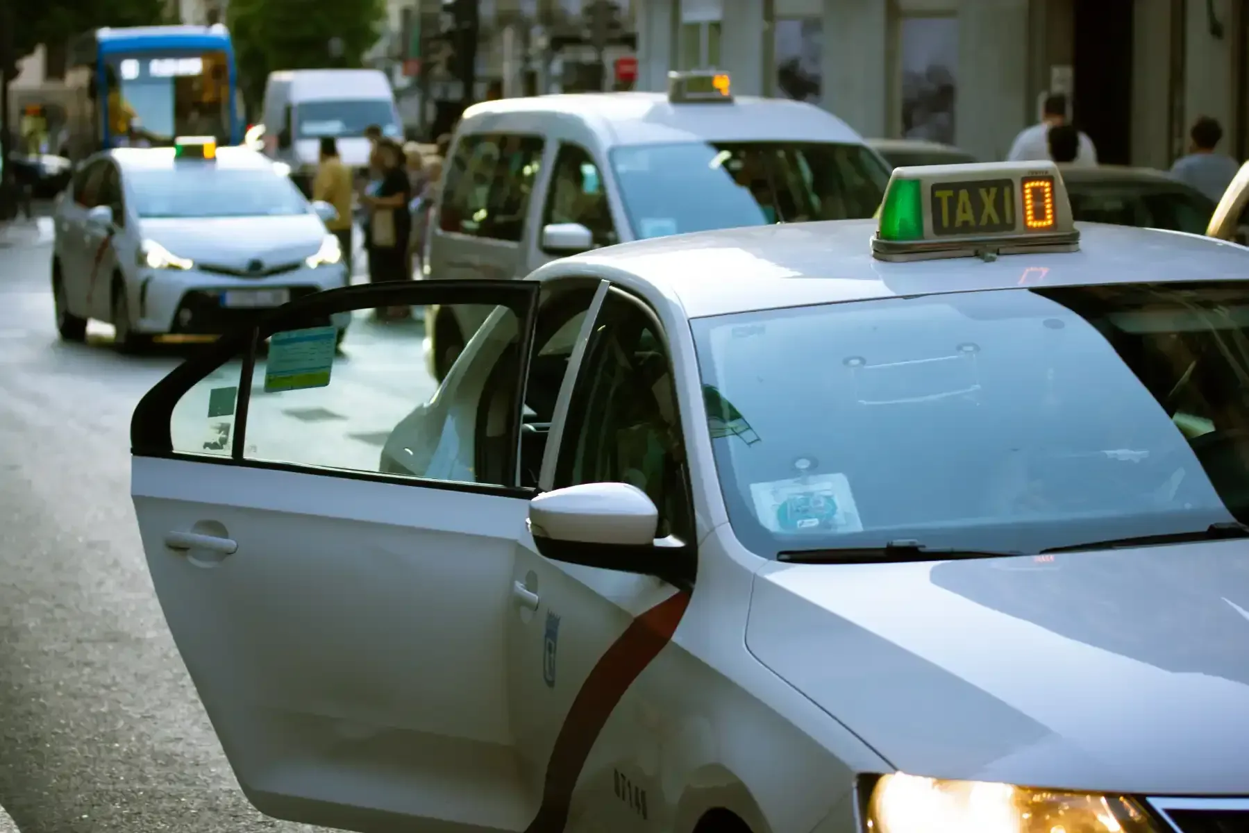 Un taxi con la puerta abierta circula por la calle.