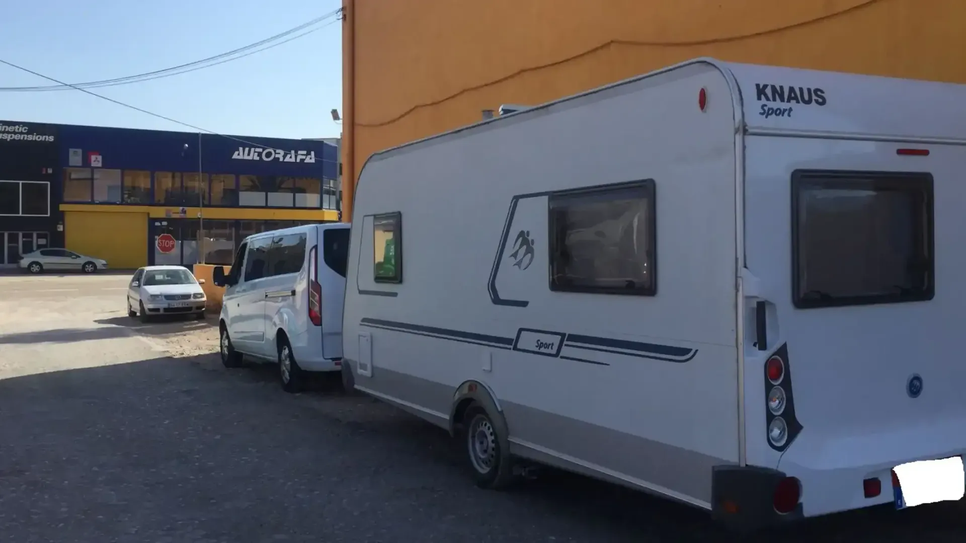 Dos furgonetas blancas están estacionadas frente a un edificio.