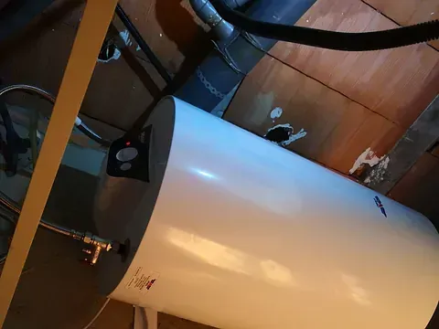 Un calentador de agua blanco está ubicado debajo del techo de una habitación.