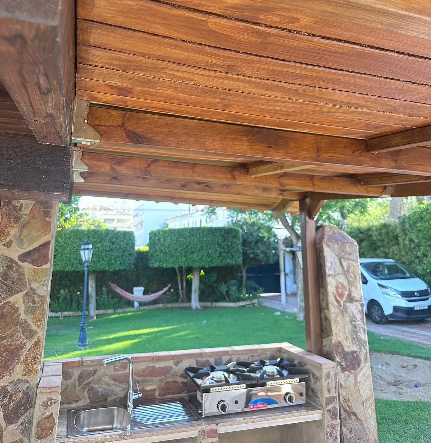 Un techo de madera sobre una cocina con una hamaca al fondo.