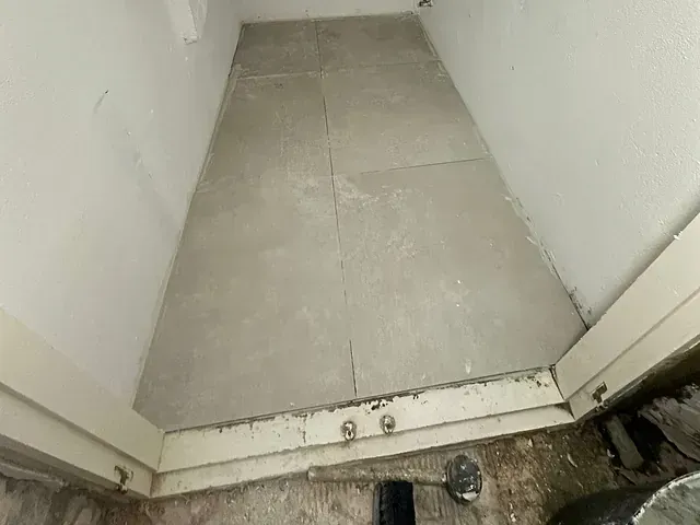 Un baño con suelo de baldosas y puerta.