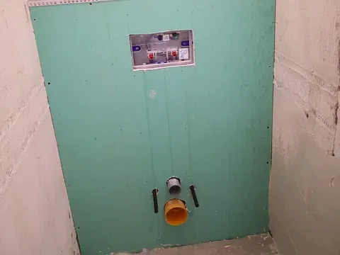 Se está construyendo un inodoro en un baño con una pared verde.