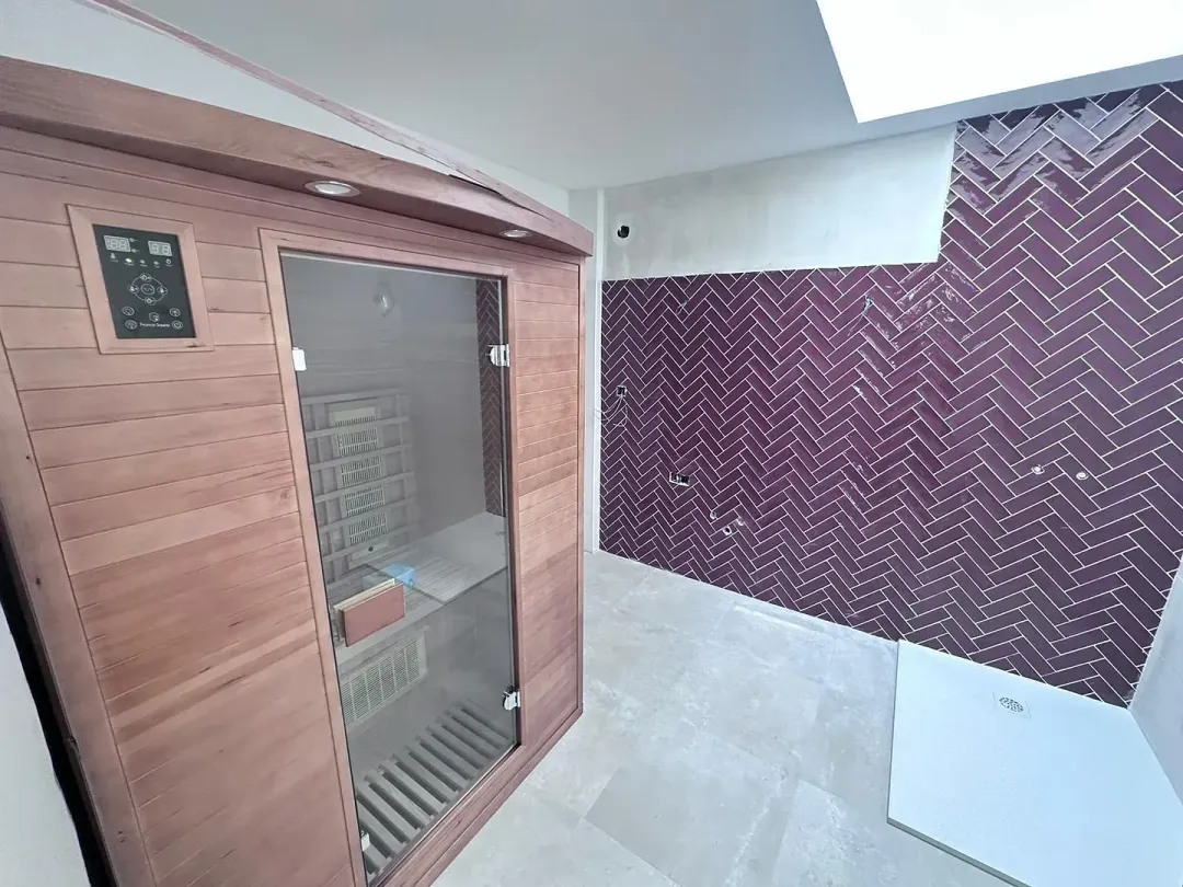 Una sauna de madera en un baño con azulejos morados en la pared.
