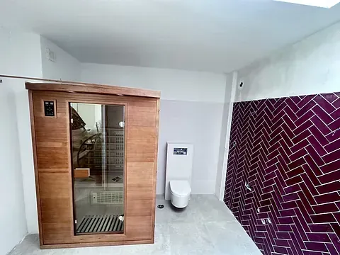 Un baño con azulejos morados y una sauna de madera.