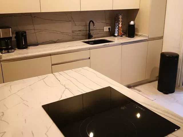 Una cocina con gabinetes blancos y un horno negro.