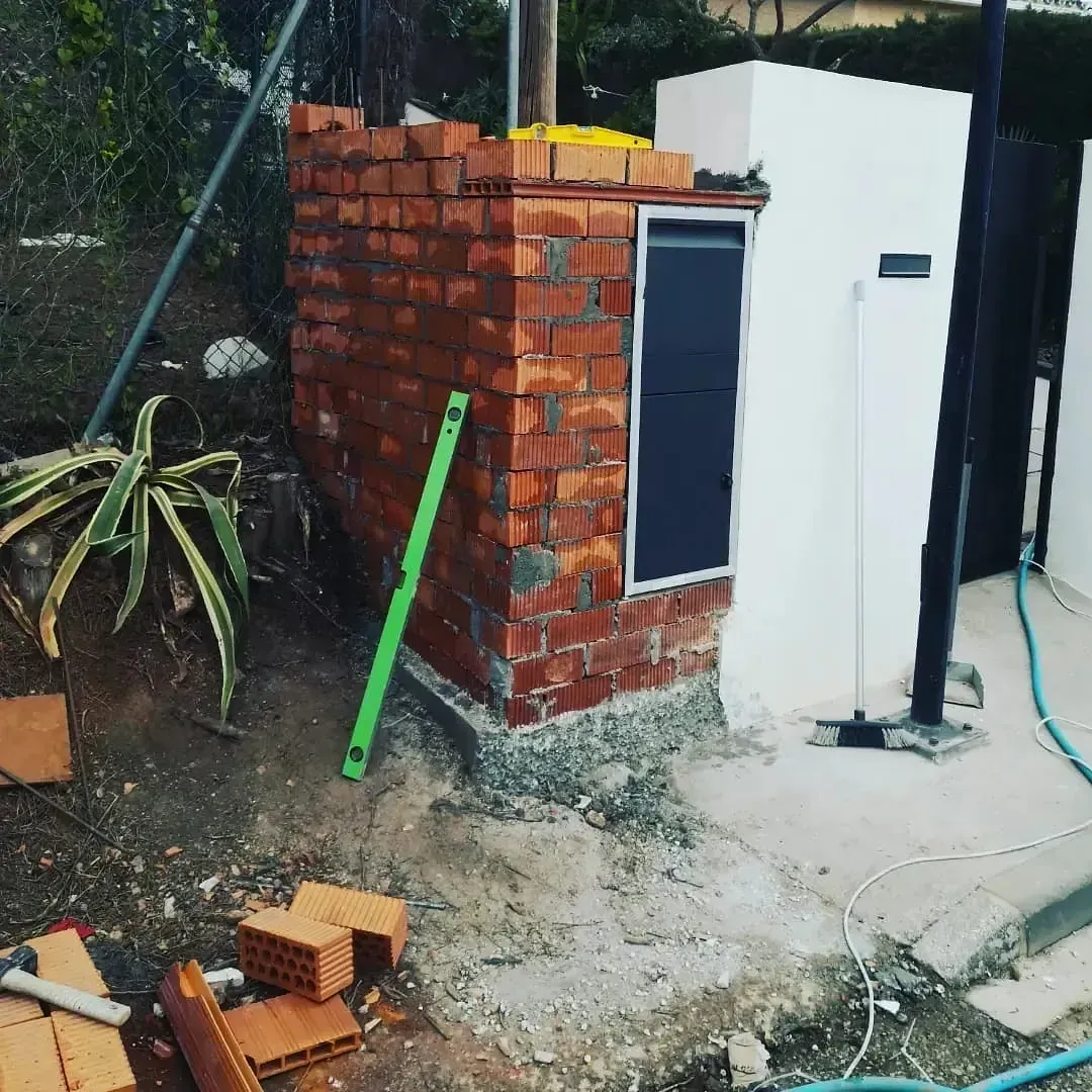 Un nivel verde está sentado al lado de una pared de ladrillos.