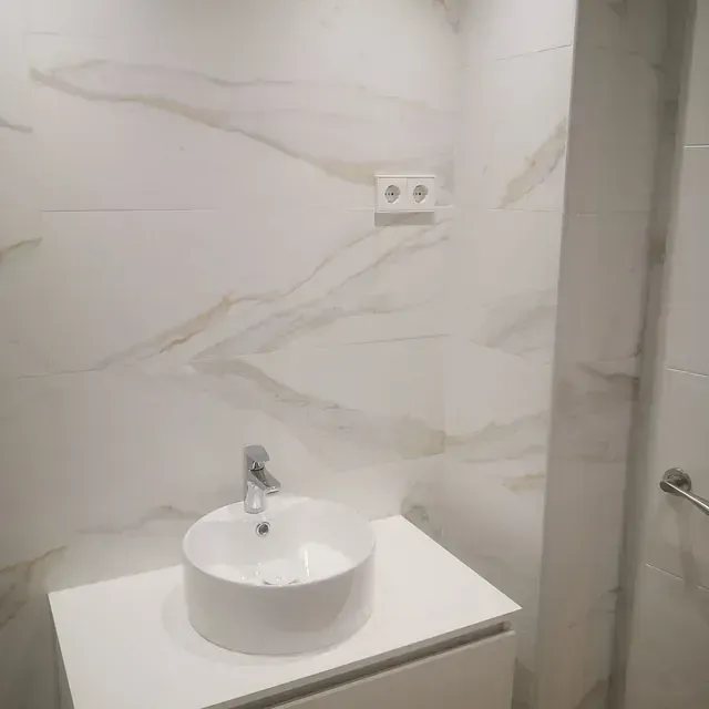 Un baño con lavabo y pared de mármol.