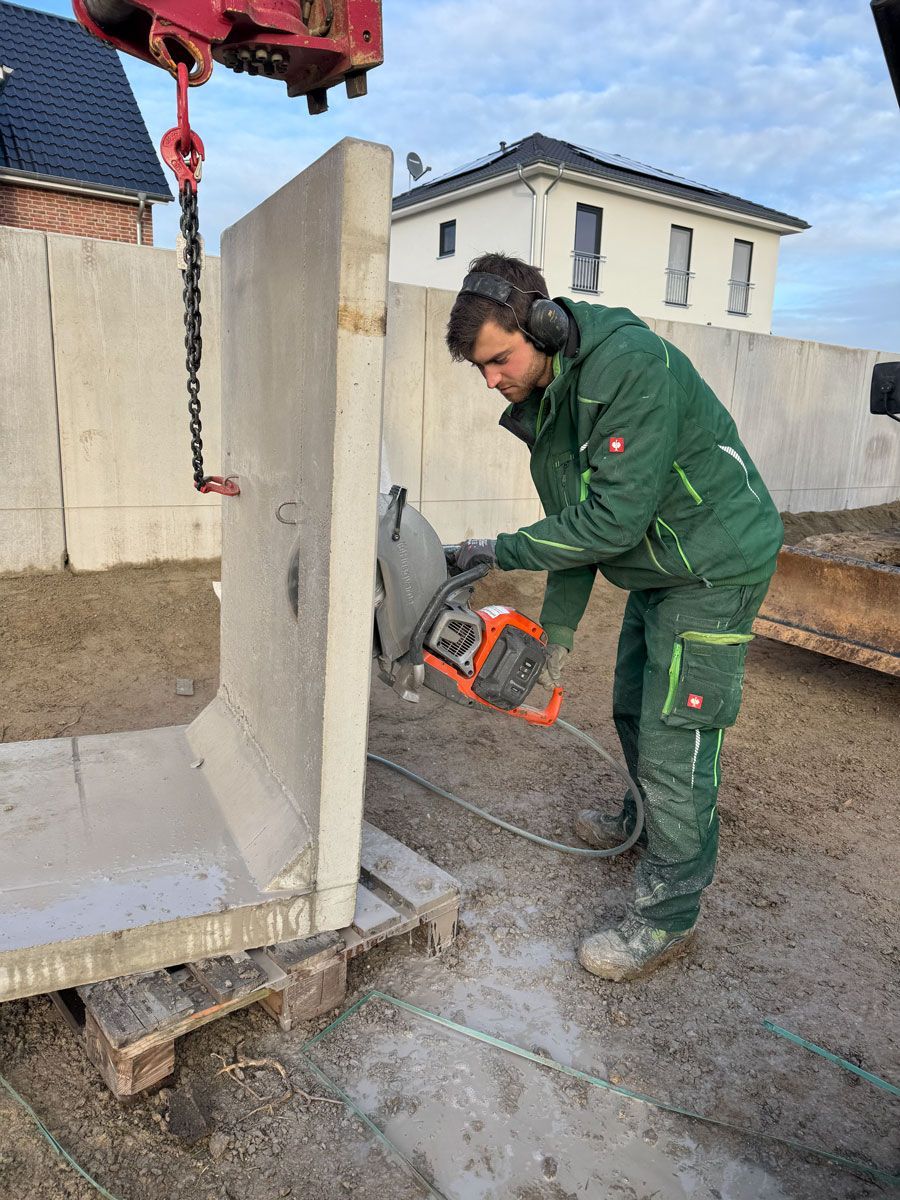 Ein Mann schneidet mit einer Kreissäge eine Betonwand.