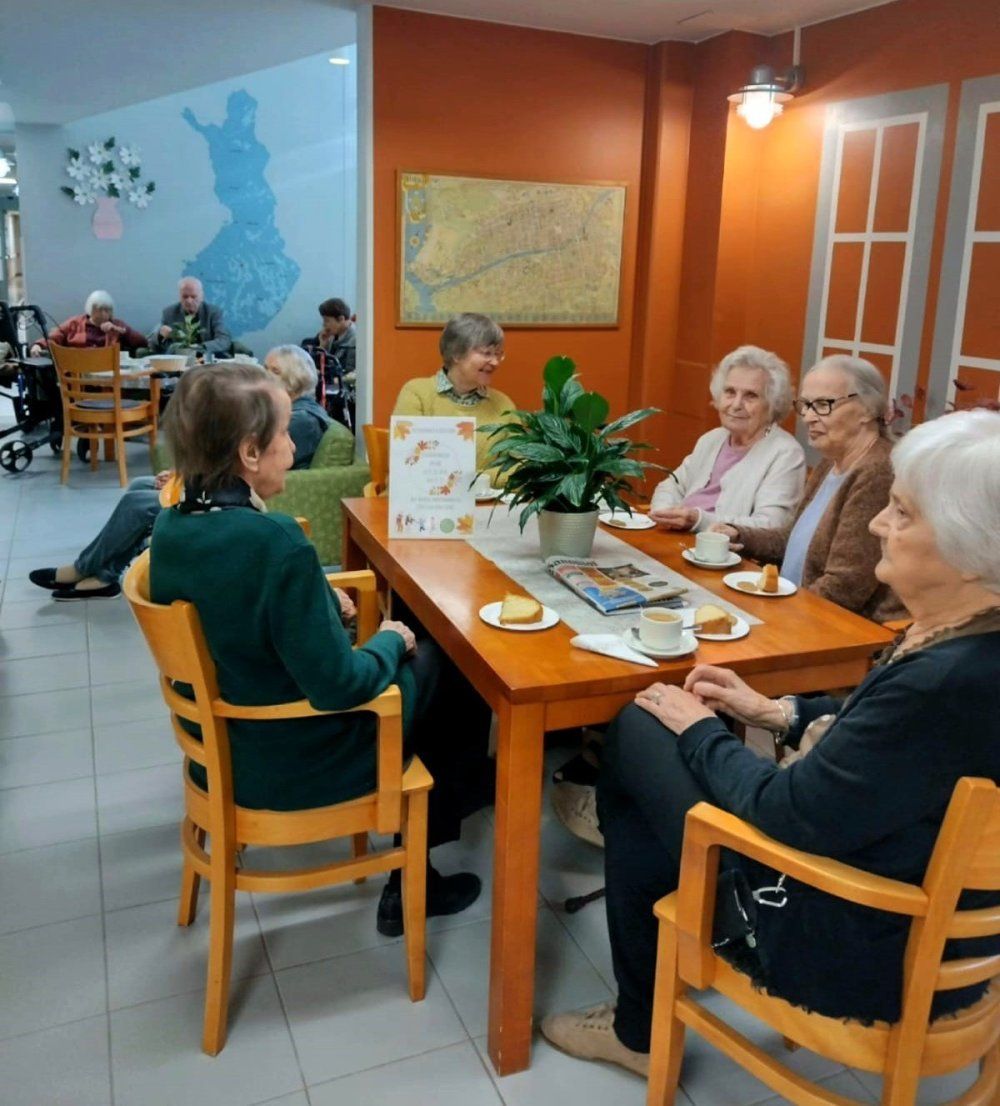 Asuinkodin asukkaat aulassa juomassa kahvia.