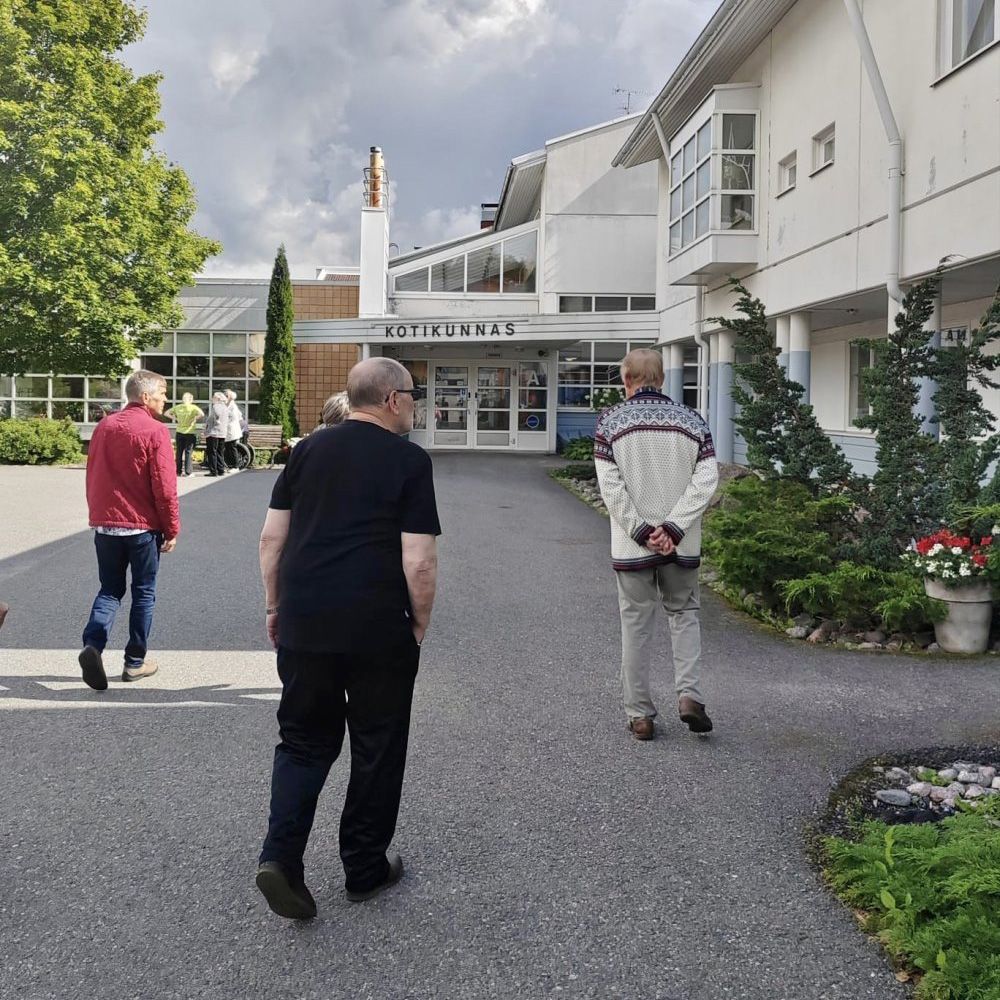 Kolme ihmistä kävelee kohti Kotikunnaan sisäänkäyntiä.