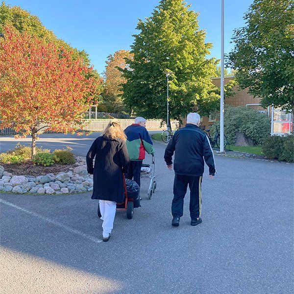 Kolme ihmistä kävelee ulkona aurinkoisena päivänä.