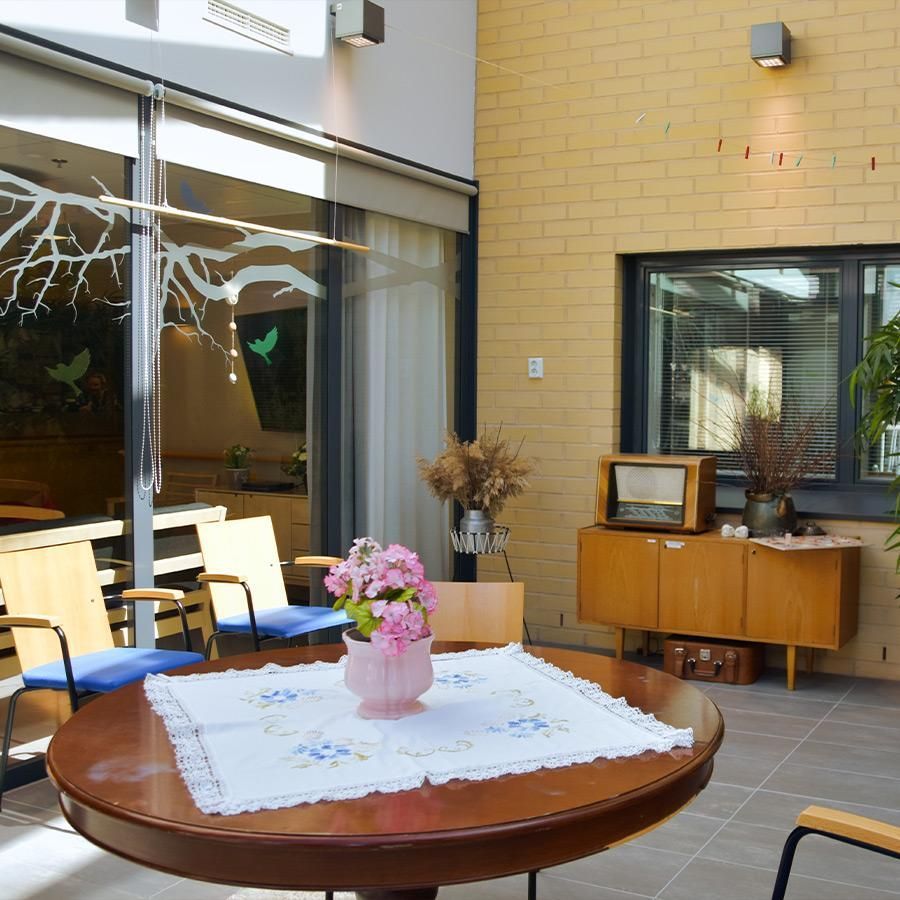 Sisätila, jossa on pyöreä pöytä, tuoleja ja puisen senkin päällä vintage-radio.