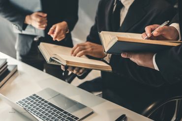 Mehrere Personen besprechen sich mit Büchern in den Händen