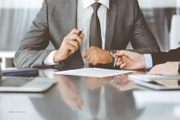 Ein Mann im Anzug soll ein Dokument unterschreiben