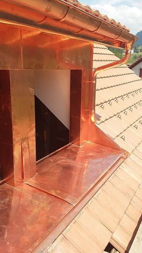 Il y a une gouttière en cuivre sur le toit d'un bâtiment.