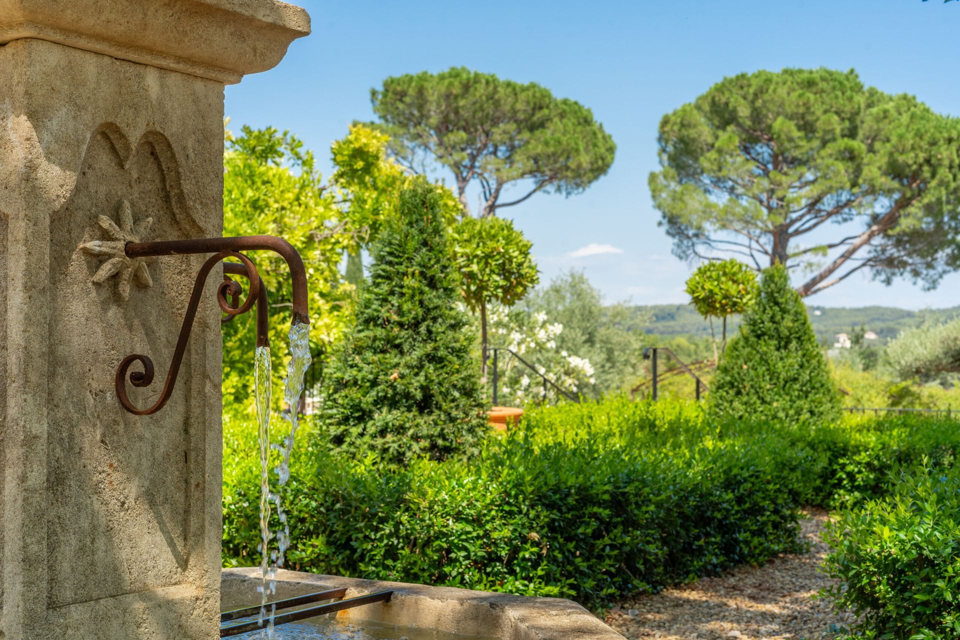 Une fontaine à eau dans un jardin avec des arbres en arrière-plan.