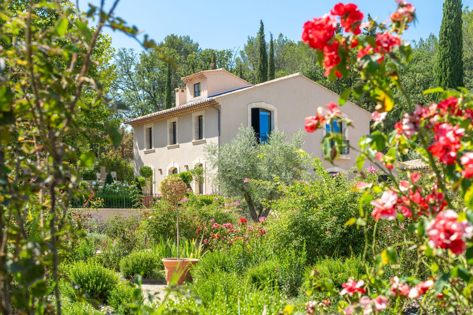 Une maison est entourée de fleurs et d'arbres dans un jardin.