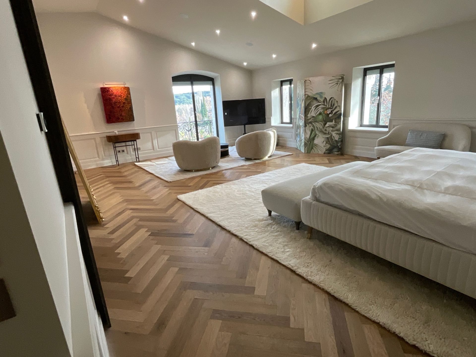 Une chambre avec un grand lit, des chaises, un tapis et une télévision.