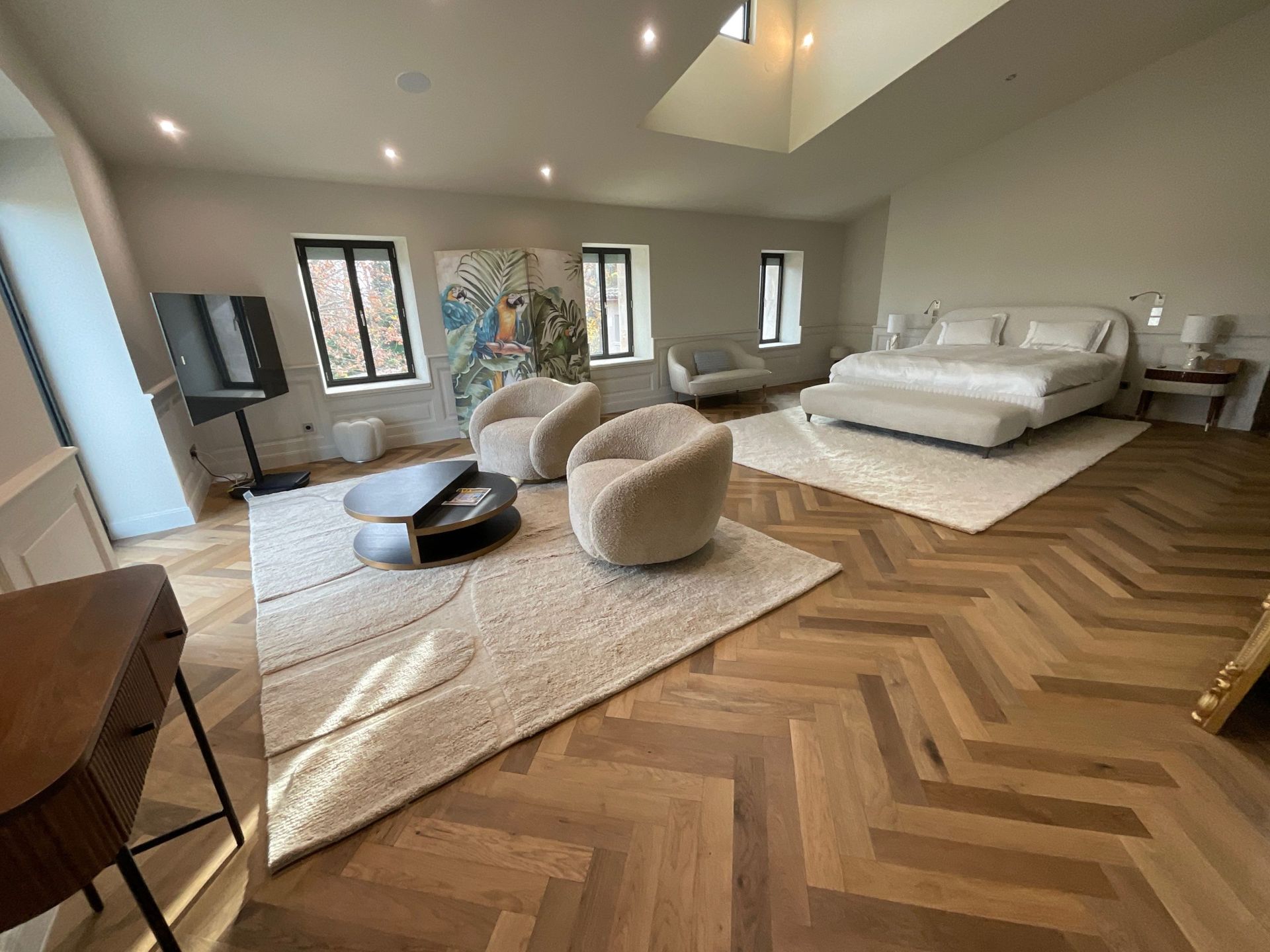 Une grande pièce avec un lit, des chaises, une table basse et un tapis.