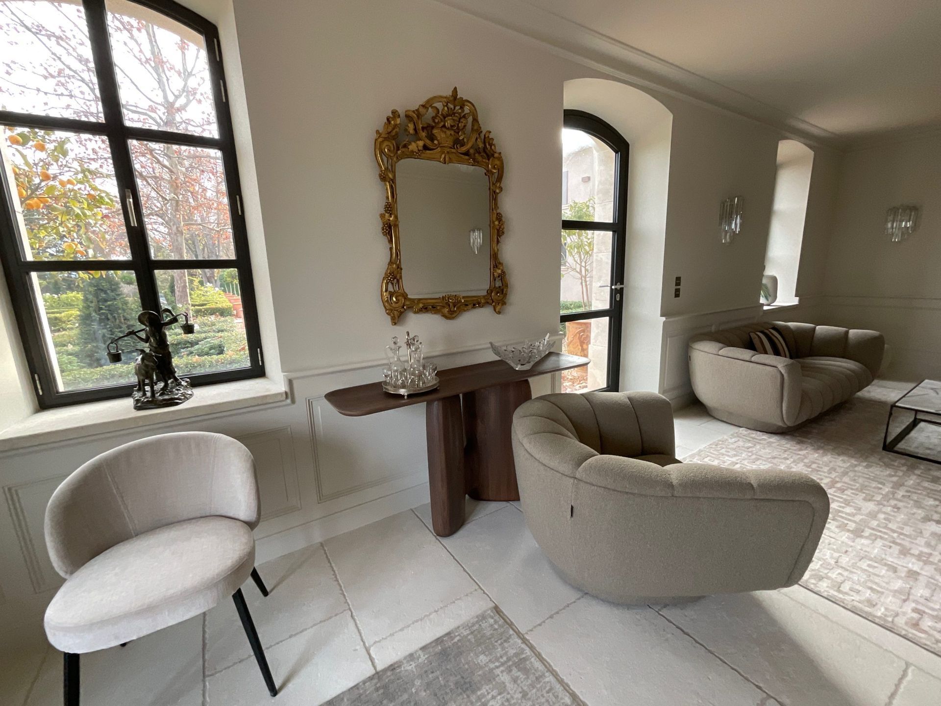 Un salon avec un canapé, une chaise, une table et un miroir.