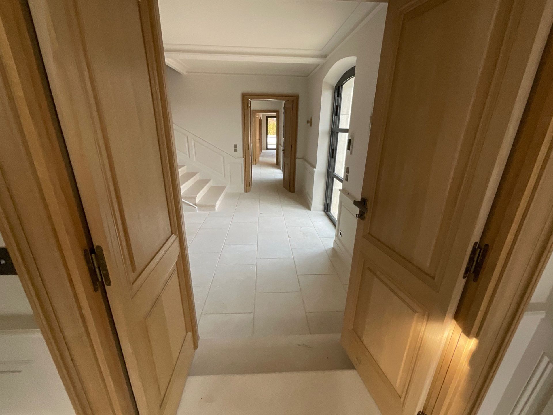 Un couloir avec des portes et des escaliers en bois dans une maison.