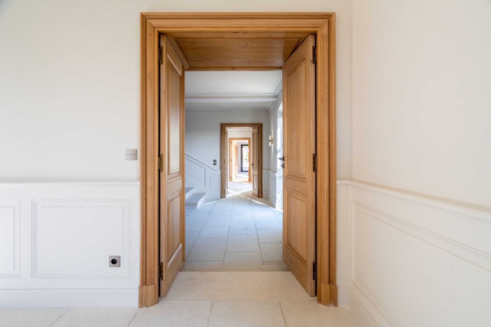 Un couloir vide avec une porte en bois menant à un escalier.