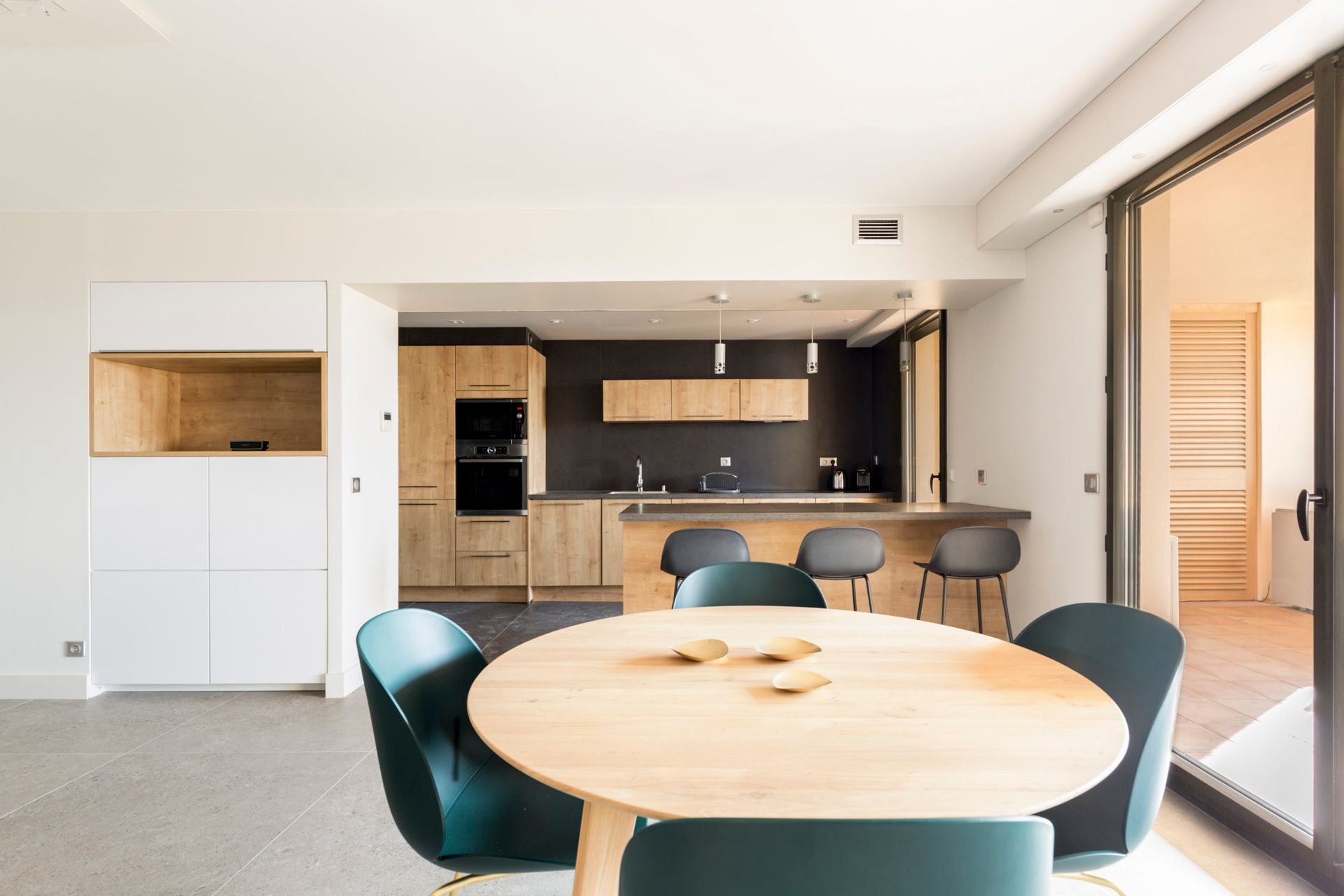 Une salle à manger avec une table ronde et des chaises devant une cuisine.