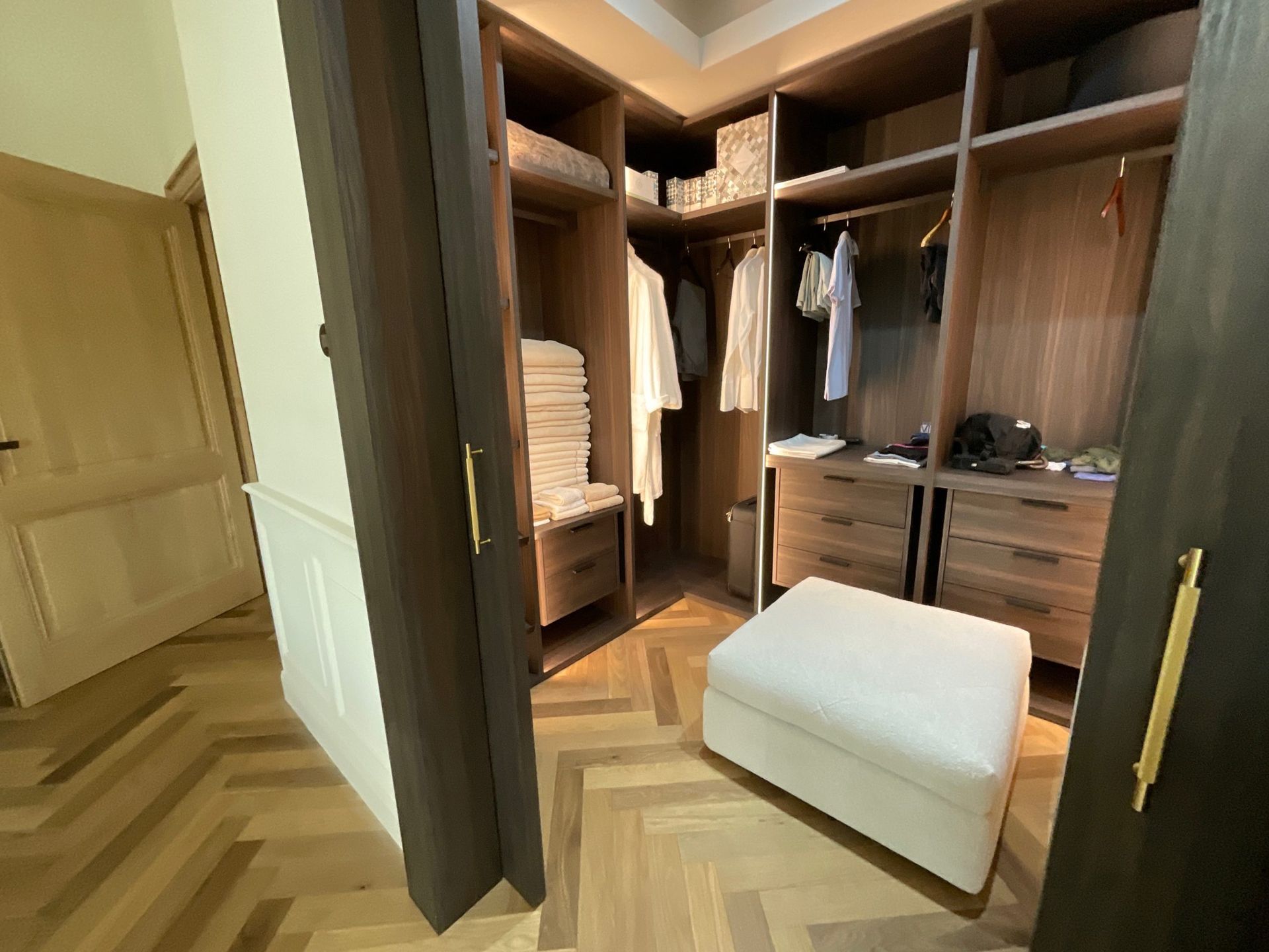 Un dressing avec un pouf blanc au milieu.