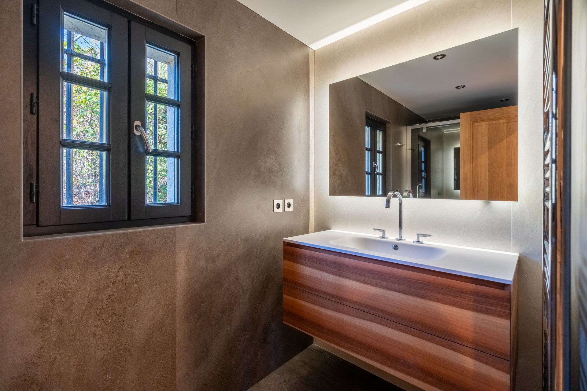 Une salle de bain avec lavabo, miroir et fenêtre.